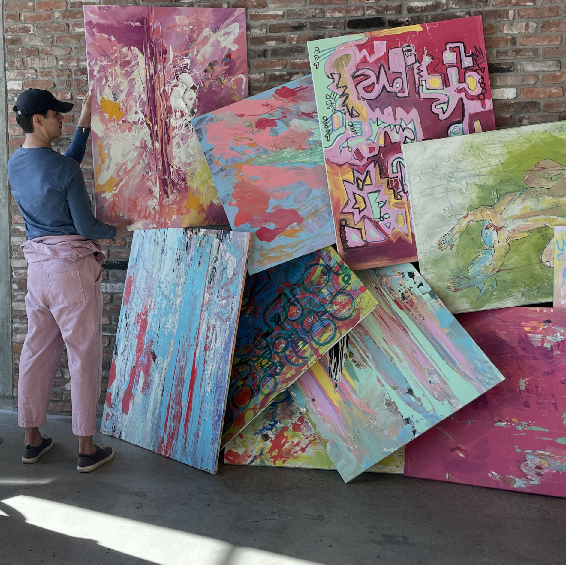 Art Jam participant arranging a colorful stack of collaborative paintings